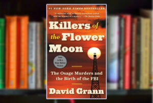 Killers of the Flower Moon book cover in front of a shelf of books