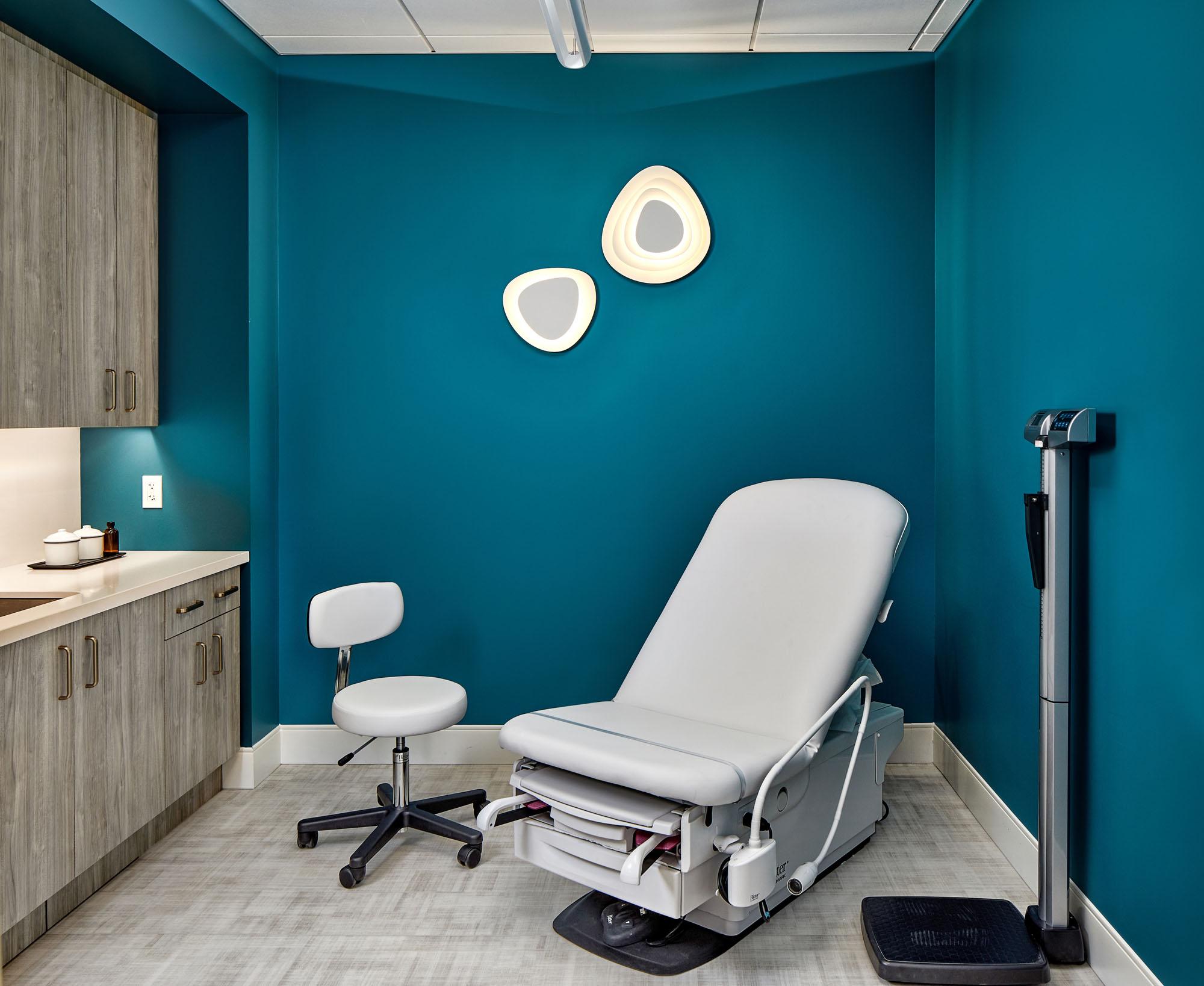 a medical exam room designed at liv by advantia health features dark blue walls and patient chair