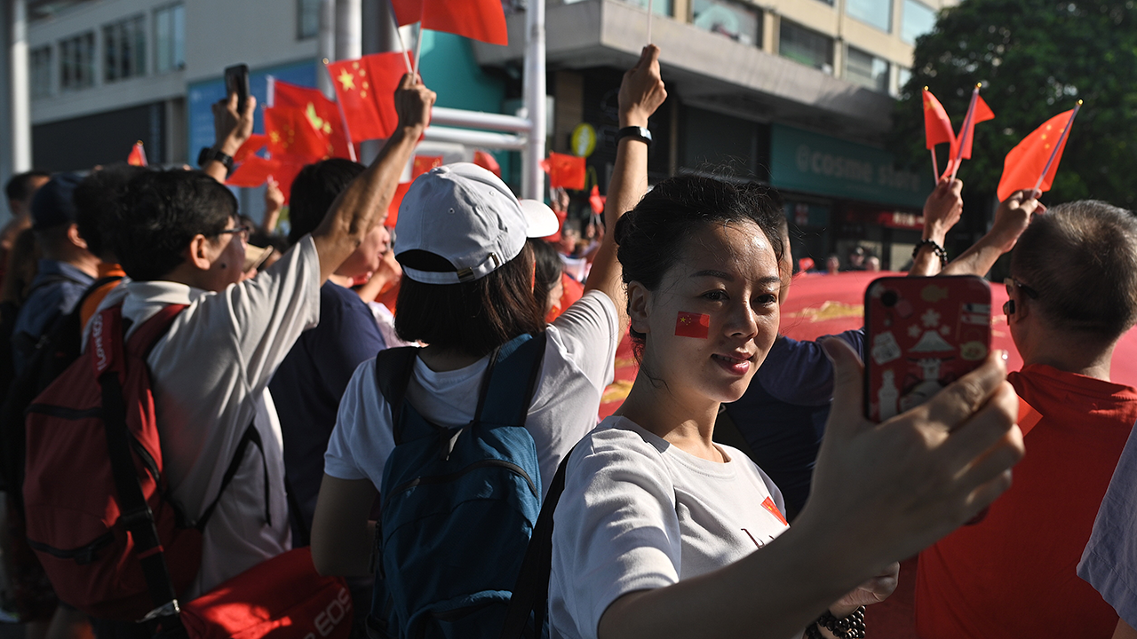 An image of a woman taking a selfie during a pro-Beijing flash mob rally in Hong Kong on Oct. 1, 2019, to mark the 70th anniversary of communist China's founding. (Philip Fong/AFP via Getty Images)
