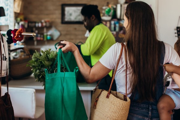 Young Australian mixed race family carries the reusable shopping bags in to the kitchen together