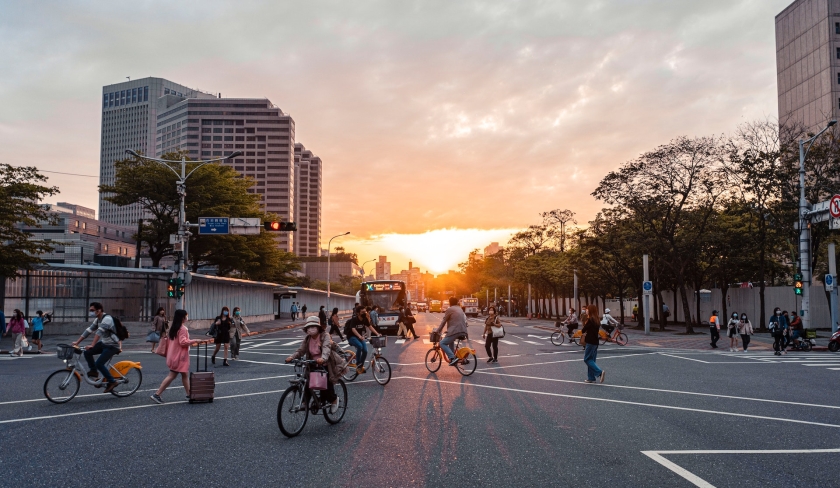 Bicycles and pedestrians crossing the road with a bus in the background.