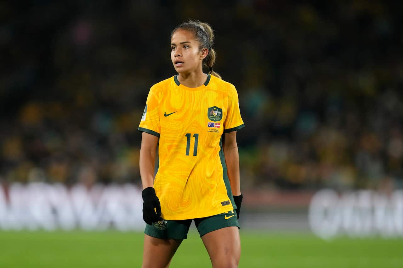 A woman wearing a yellow football shirt and black gloves