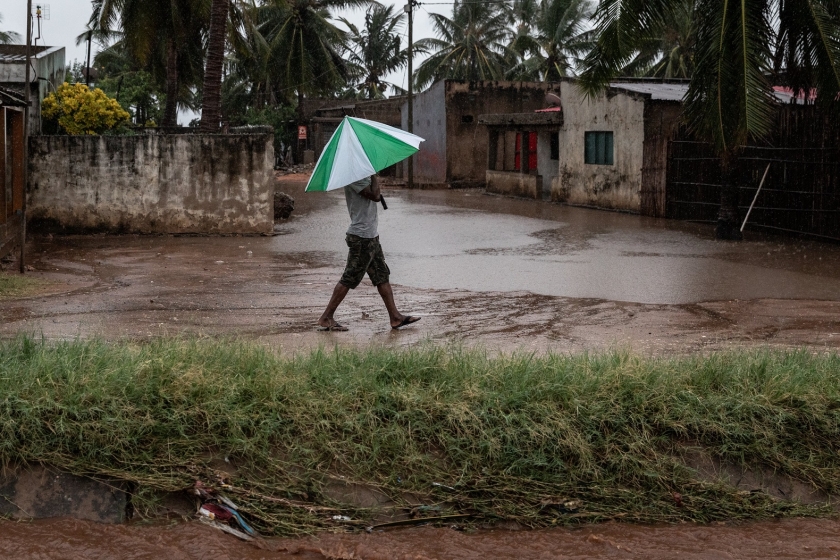 A woman walks in a storm in Cabo Delgado