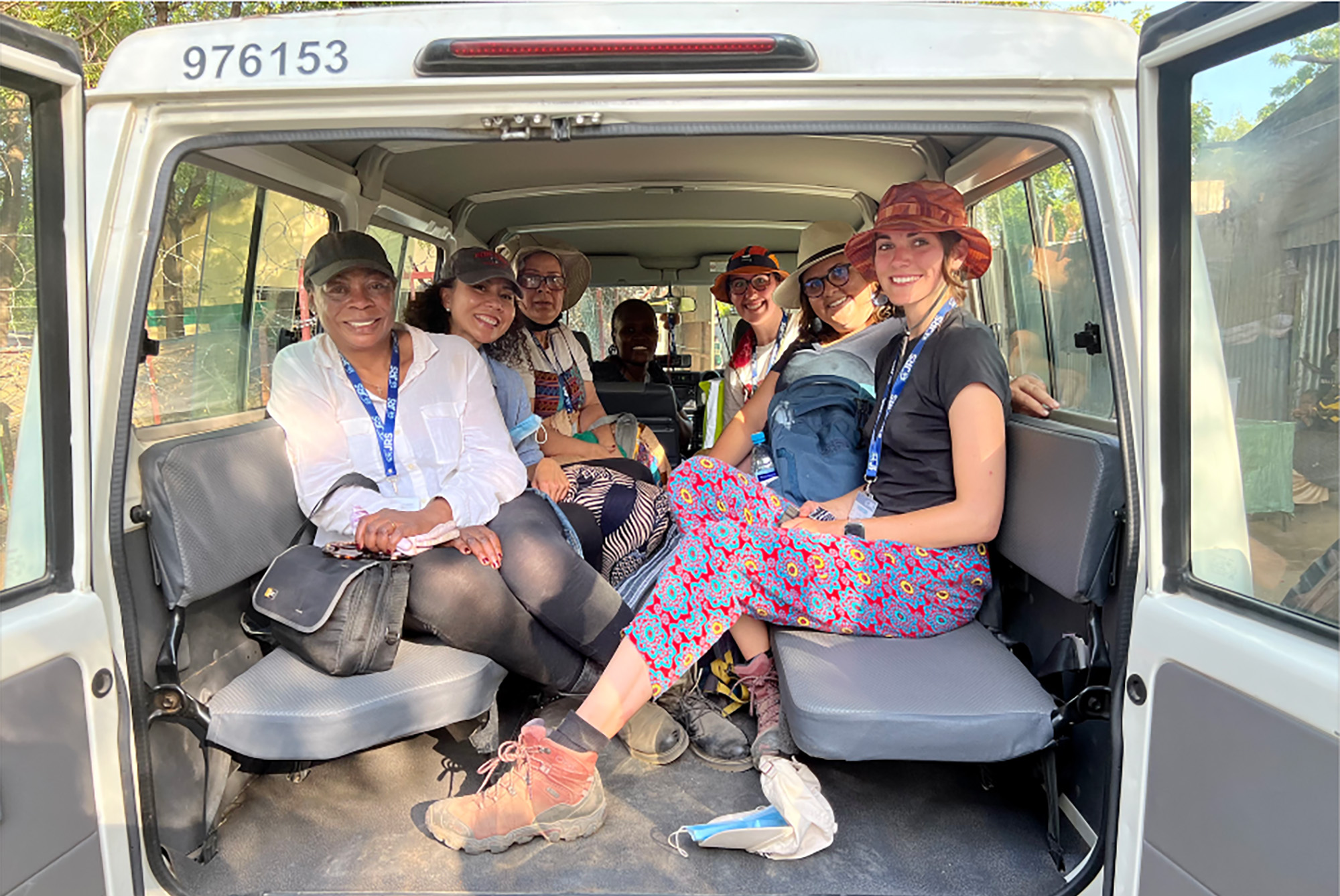 Photo:  A group of woman sit in a van all wearing various types of hats and comfortable clothing.