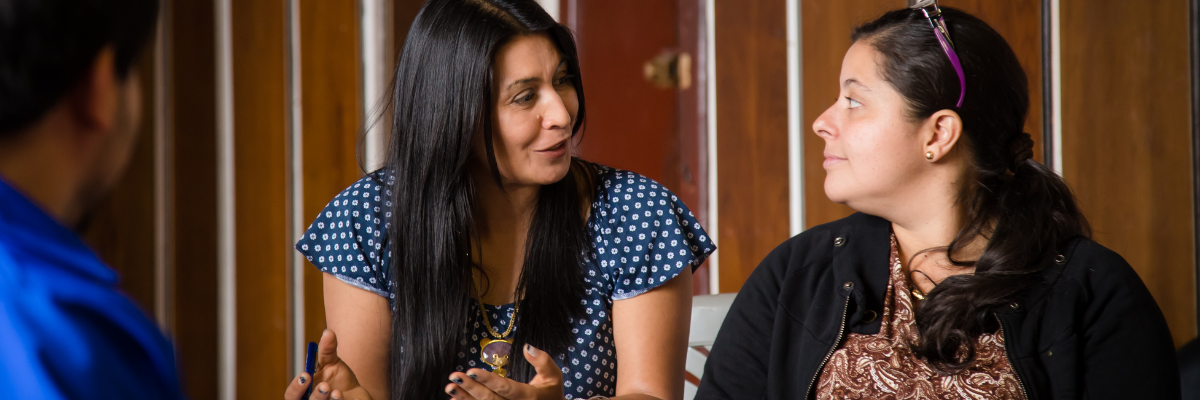 Image shows two woman sat together and discussing
