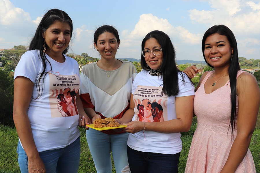 women smiling while holding a plate of sweets